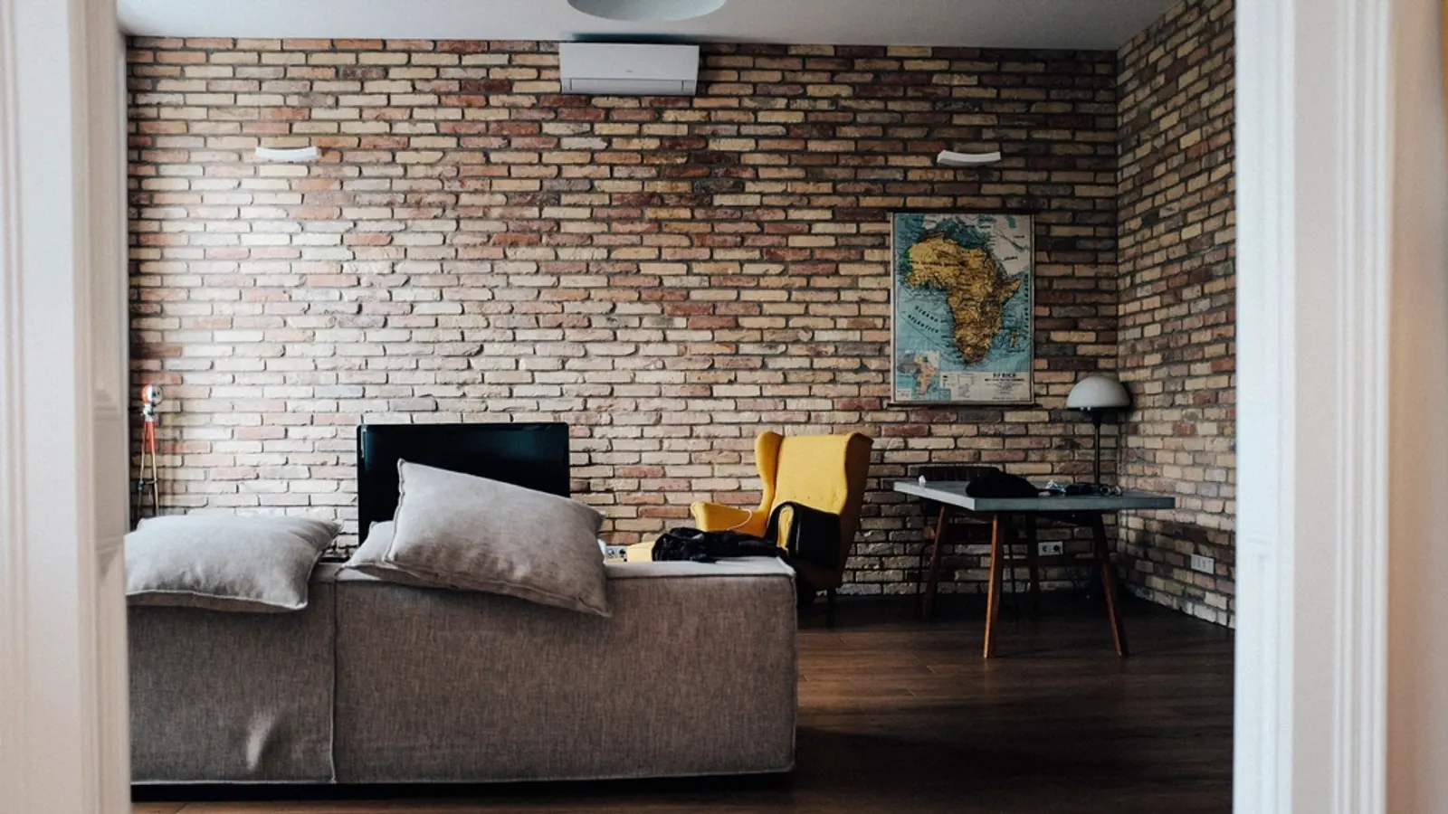 Living room with a sofa, armchair and a TV against an exposed brick wall